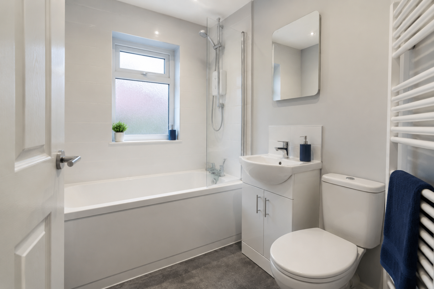 Clean white family bathroom with electric shower over bath and vanity unit, London